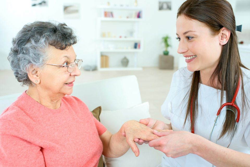 Nurse inspecting elderly lady's hand