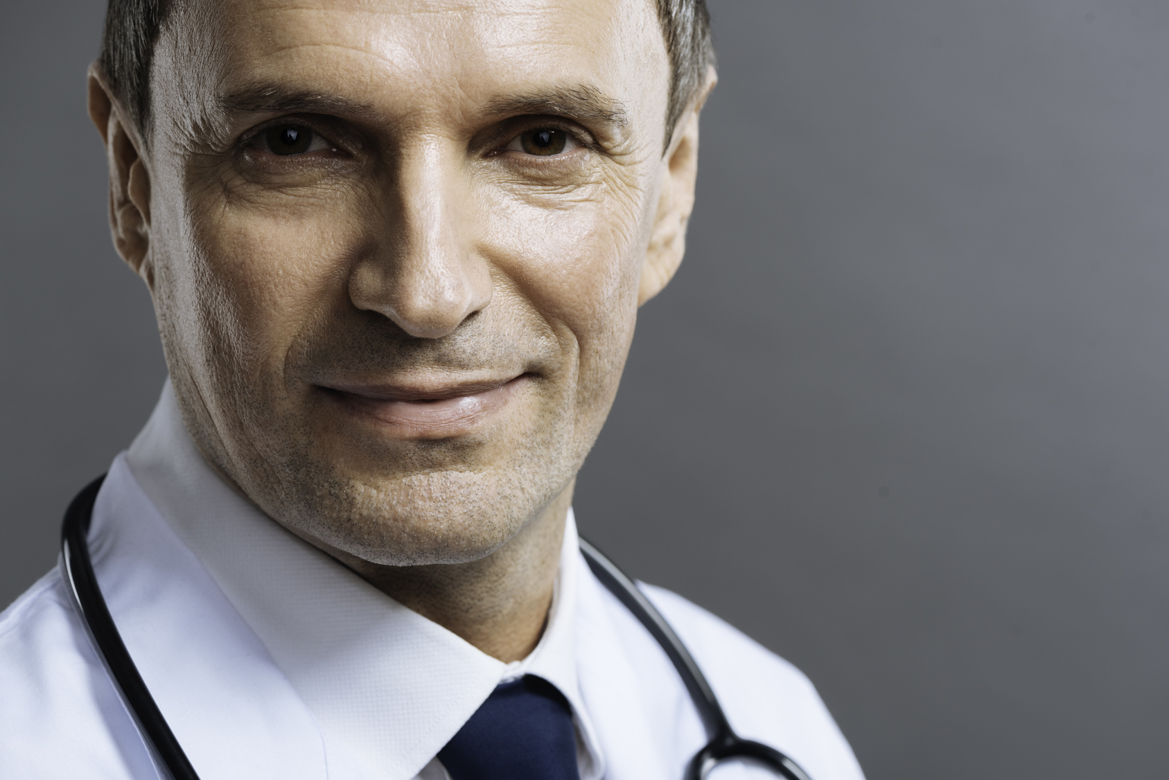 Portrait of handsome doctor smiling on a grey background