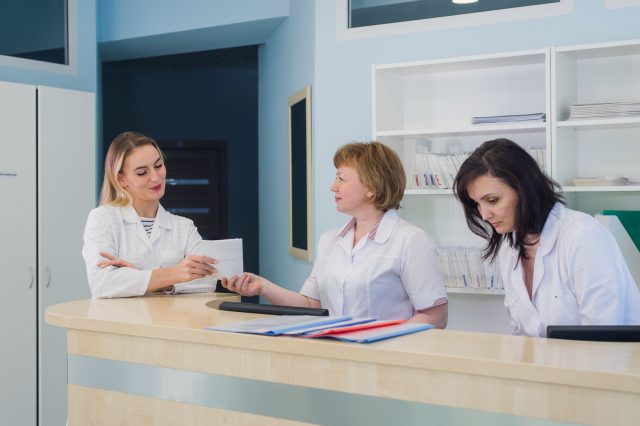 Doctors having discussion hospital reception while people sitting in background