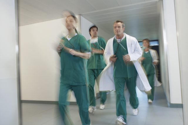 Motion blur shot of doctors and nurses in scrubs running through hospital corridor