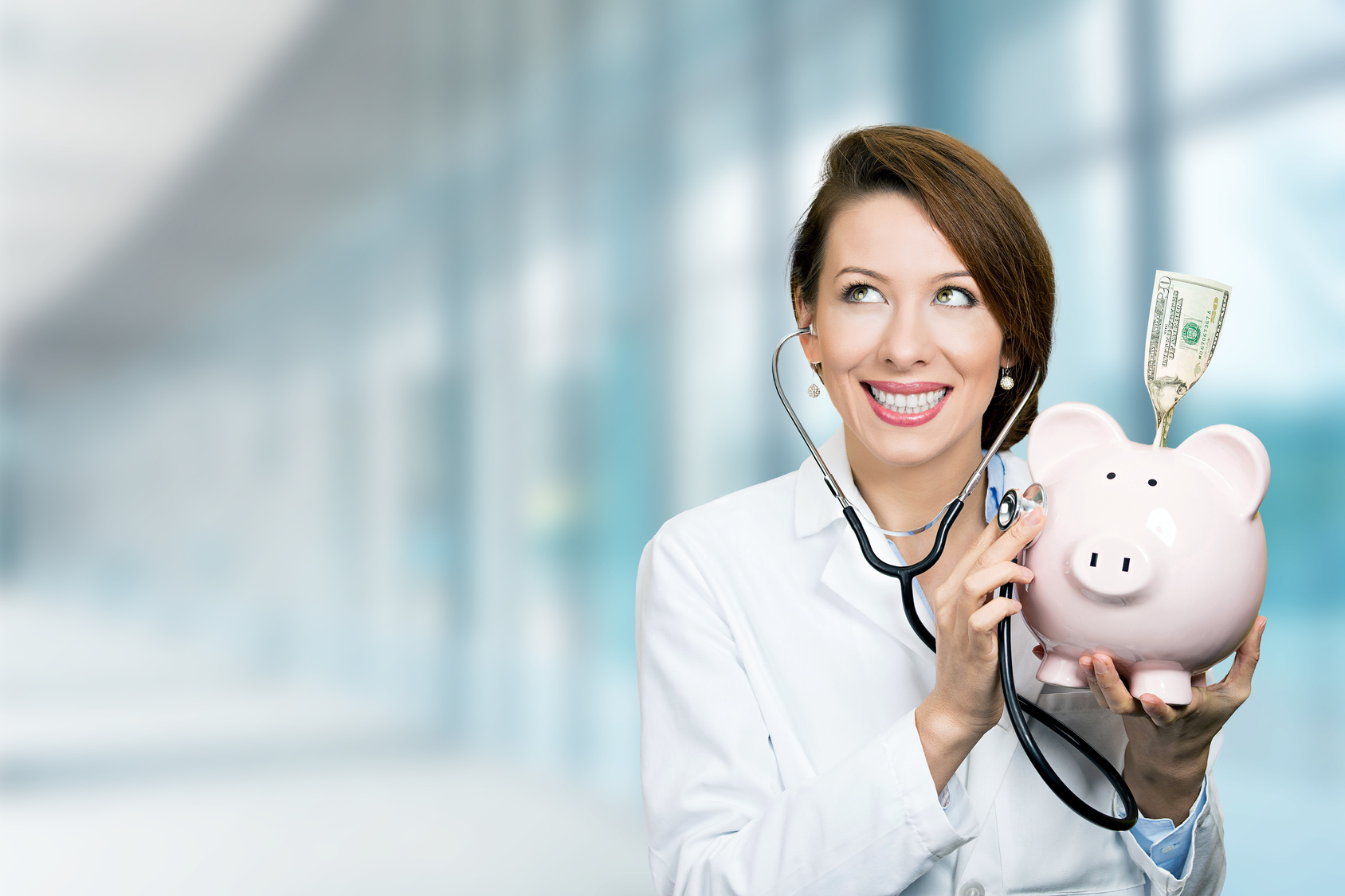 smiling doctor holding listening to piggy bank with stethoscope