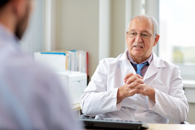 senior doctor talking to male patient at hospital