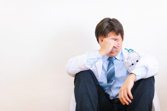 Frustrated medical doctor sitting on floor
