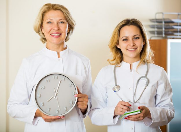 Time for appointment: mature and young doctors with clock