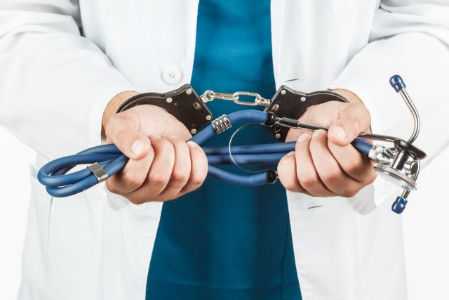 Close-up Of Doctor Hands With Stethoscope In Handcuffs.