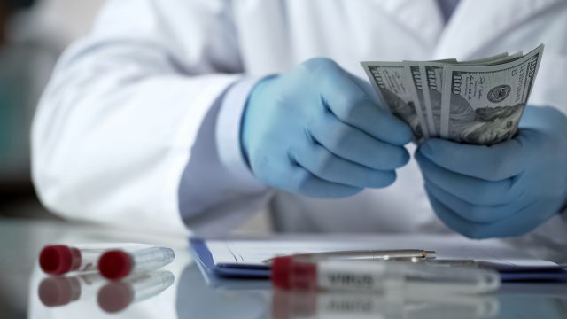Doctor hands counting money on table, financing clinic experiments, bribery