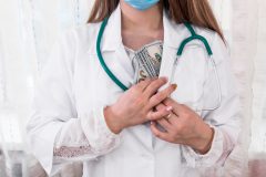 Doctor hiding dollar bribe into robe, corruption in medicine
