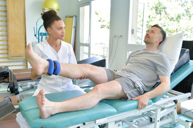 female physiotherapist massaging the leg of patient