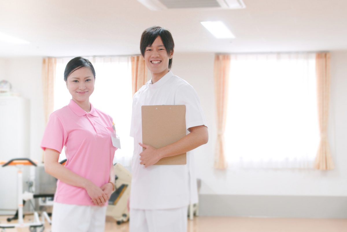 リハビリ室に立つ女性理学療法士と男性看護師