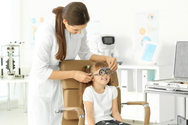 Ophthalmologist examining vision of little child in clinic